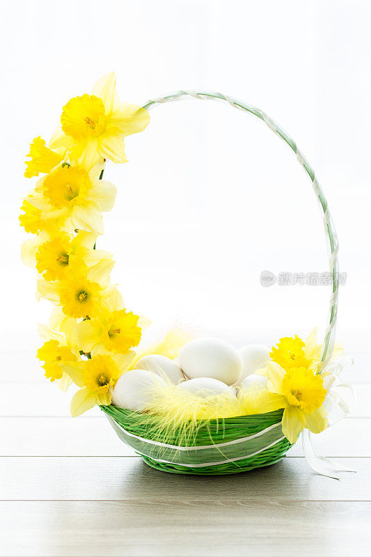 复活节彩蛋和春天的水仙花放在一个篮子里