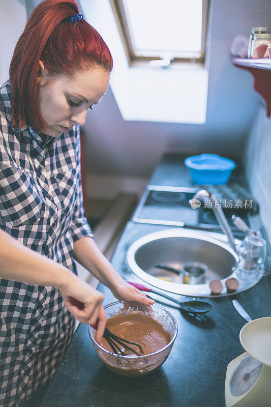 美丽的女人在家里准备饼干和松饼。