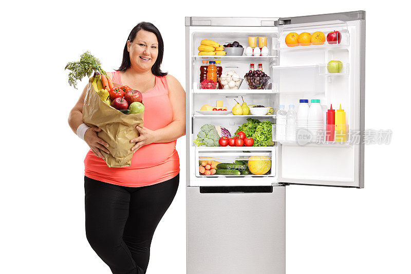 超重的女人，靠在冰箱上的杂货袋