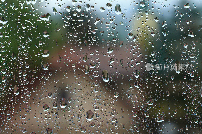 雨点落在窗户上，房子和教堂是背景