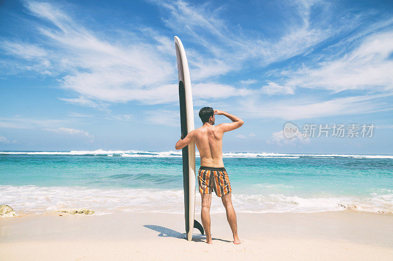 年轻的冲浪者带着冲浪板在海滩上享受。