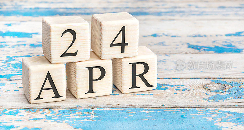 4月24日。木制立方体与日期4月24日在旧的蓝色木制背景。
