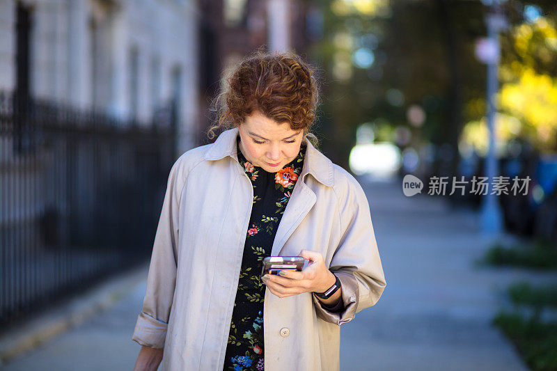 在布鲁克林街上看手机的女人