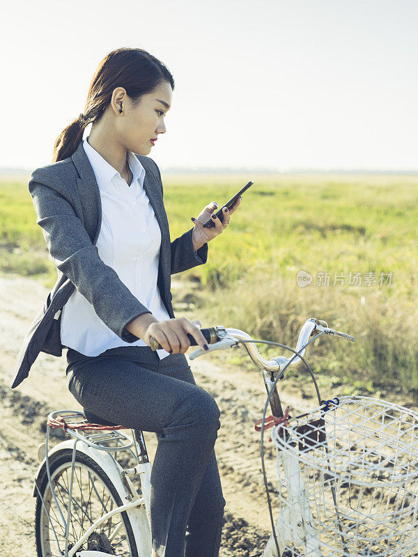 年轻的女商人，一边骑车一边用手机发短信