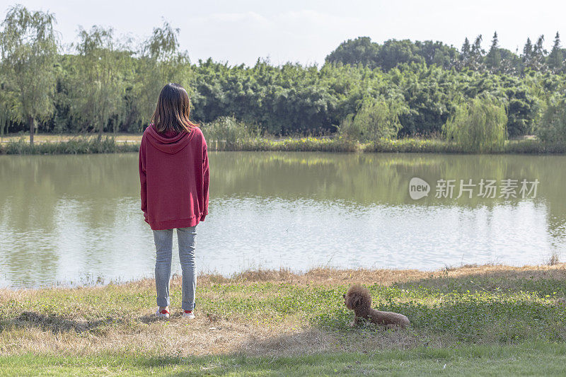 一个女人和她的小狗在湖边玩耍