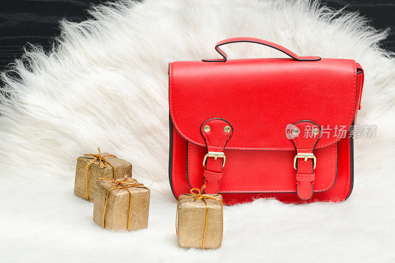 白色毛皮上的红色包和迷你礼盒。时尚的概念。假日购物