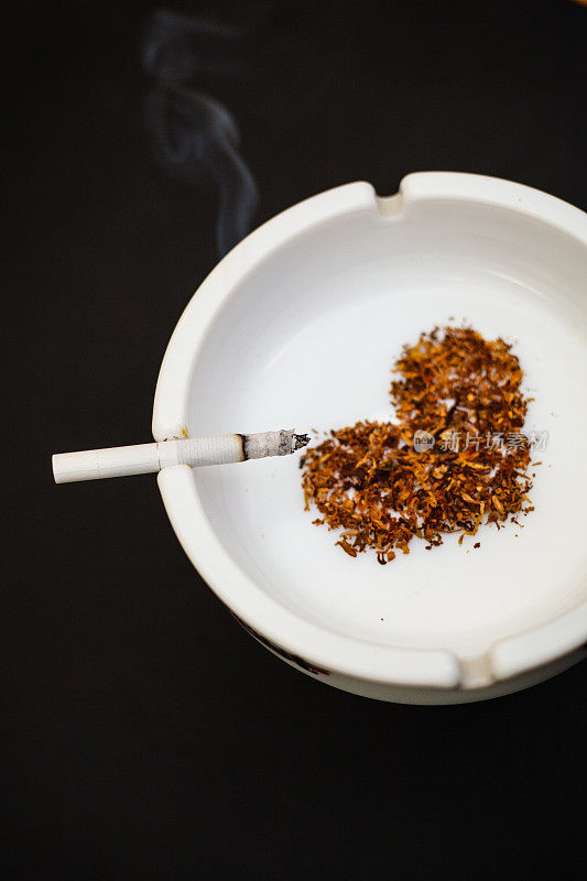 白色陶瓷烟灰缸与香烟烟雾和心型干烟叶