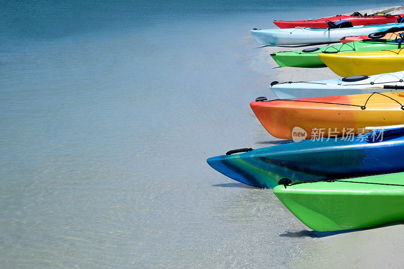 在热带海滩上，八只五彩缤纷的皮划艇排成一行