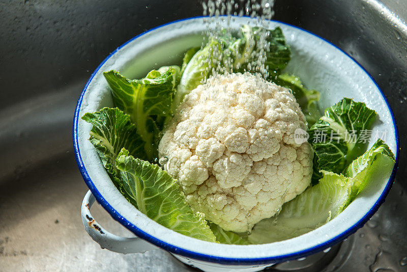 花椰菜在钢水槽中清洗，在滤锅中运行喷水龙头