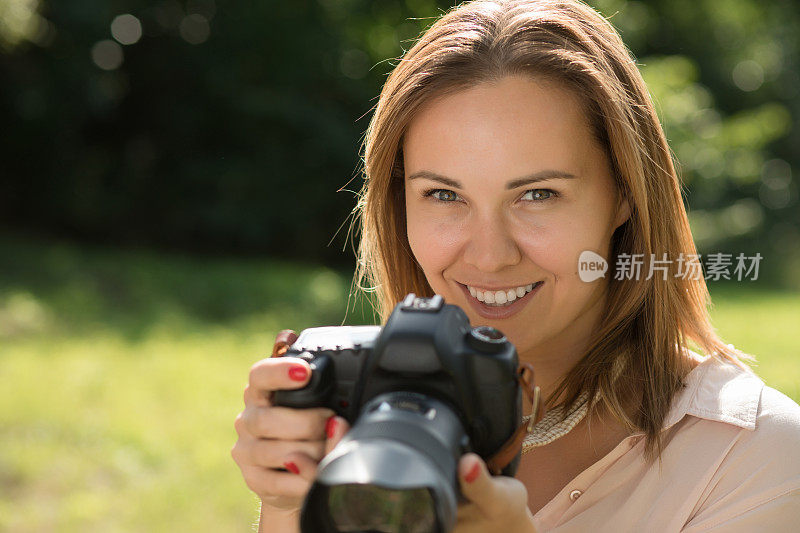 一名女摄影师拿着相机靠近她的脸拍照