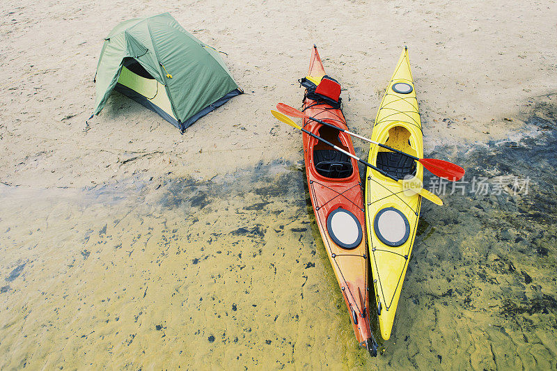 在皮艇漂流。河岸上立着一个帐篷营地。