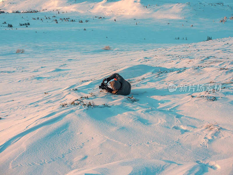 业余摄影师躺在雪地里看他的照片
