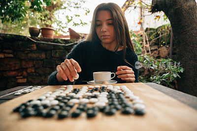 年轻女人喝咖啡玩围棋的肖像