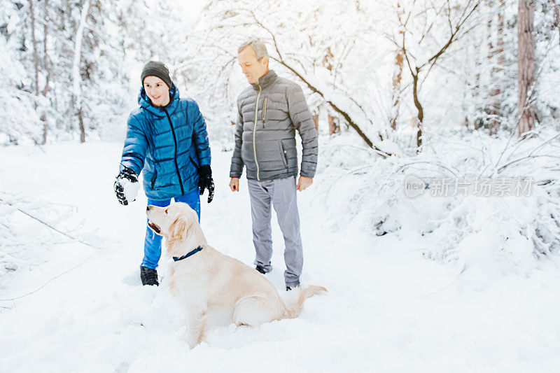 一家人和他们的狗在公园玩雪球