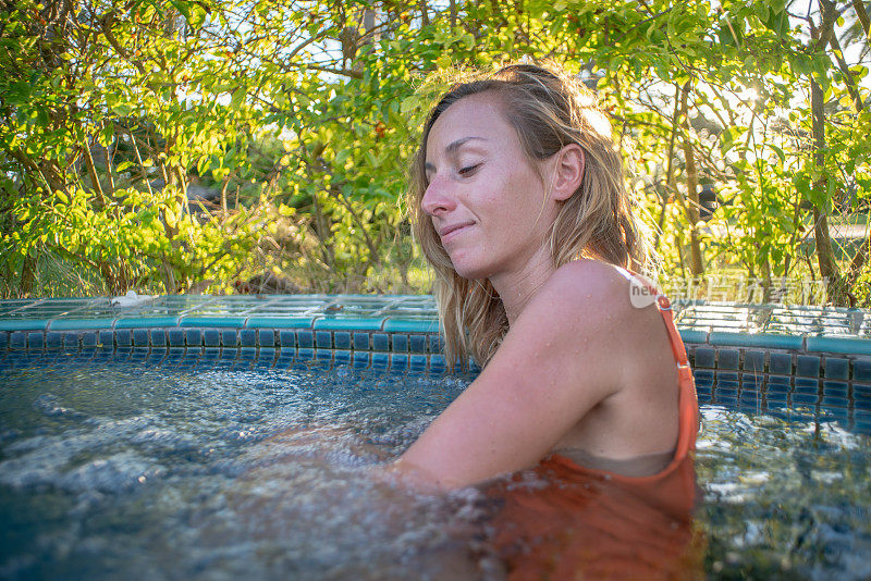 在度假村温泉的热水浴缸健康在热带天堂-女人放松在豪华度假村温泉撤退的室外热水浴缸池。快乐的年轻女模特放松休息在水上度假旅游。