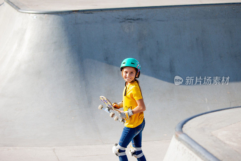 微笑的年轻滑板女孩站在滑板公园