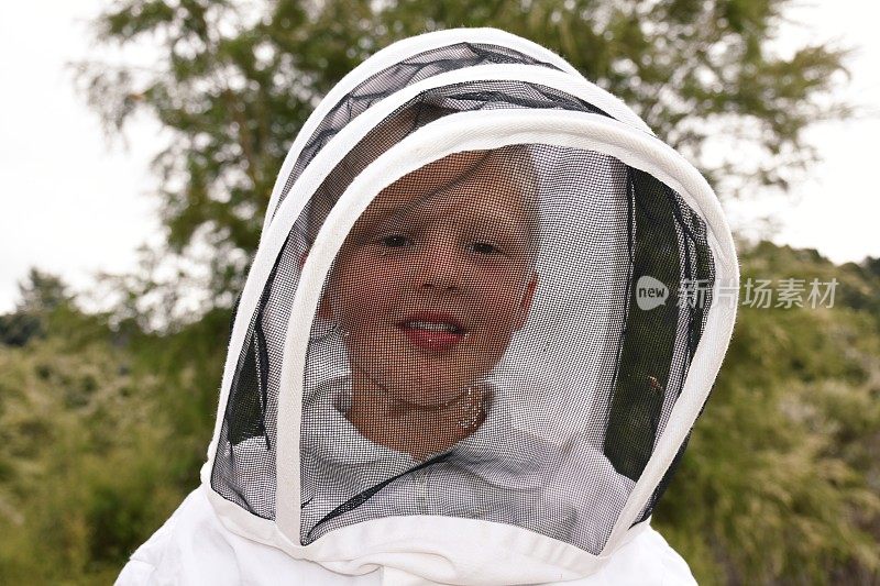 穿着蜜蜂服的孩子透过面纱品尝蜂蜜