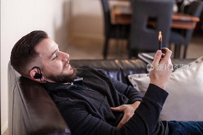 千禧一代男性在家戴耳机听音乐