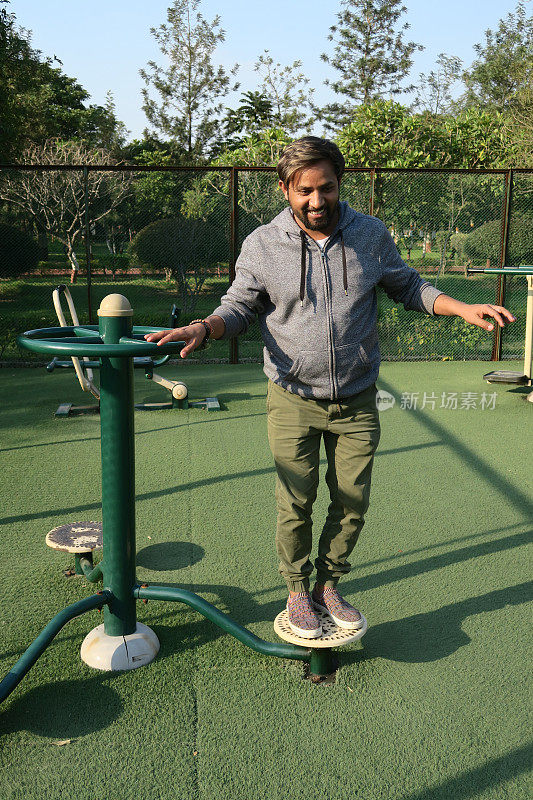印度男子在户外健身房使用身体扭转健身器材，在露天公园锻炼