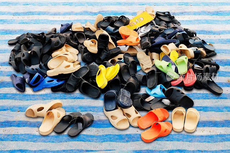 鞋子，成堆的鞋子在农村土地市场上出售各种颜色的组合，凉鞋，休闲鞋，旧的。