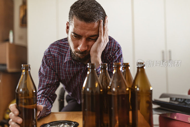 年轻悲伤的醉酒男子喝啤酒和酒精感到浪费，孤独和绝望的痛苦和情绪压力。人与酗酒、上瘾和男人抑郁的概念。