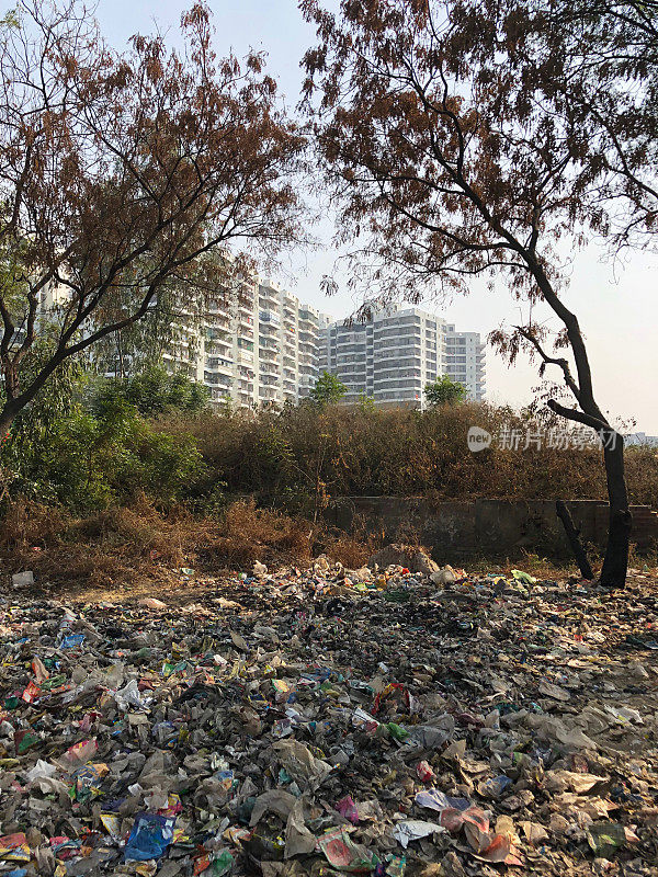 这是印度新德里郊区加济阿巴德的公寓楼旁堆积如山的危险垃圾，照片上的枯树显示了污染和垃圾填埋场