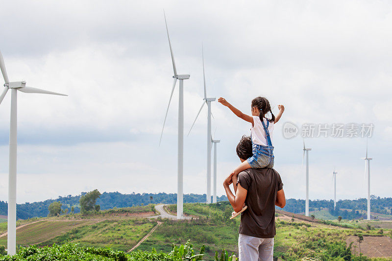 亚洲小女孩骑在父亲的肩膀上在风力涡轮机领域