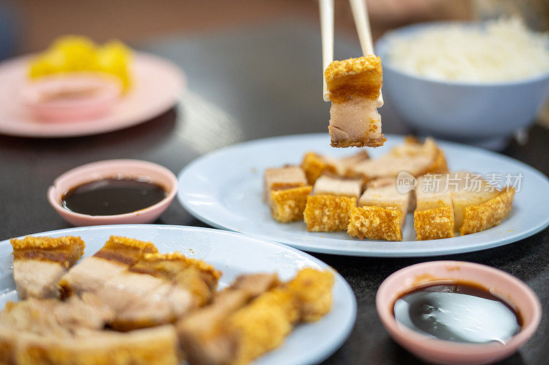 泰国餐馆里的筷子夹着香脆的烤猪肉