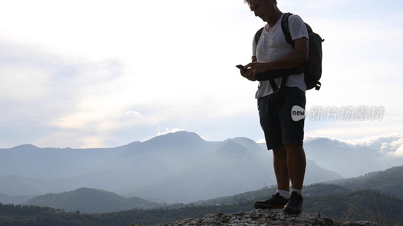 日出时分，男性徒步旅行者在山坡上休息