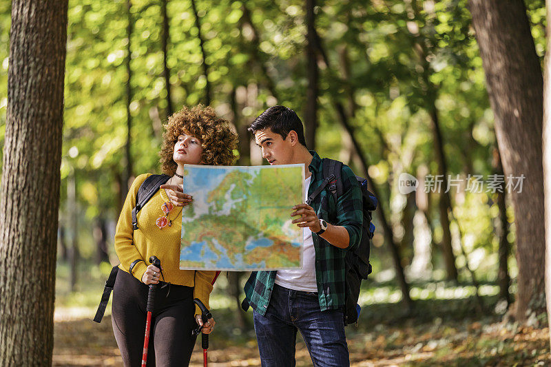 在森林里一起徒步旅行时，男人和女人在地图上寻找目的地的部分视图