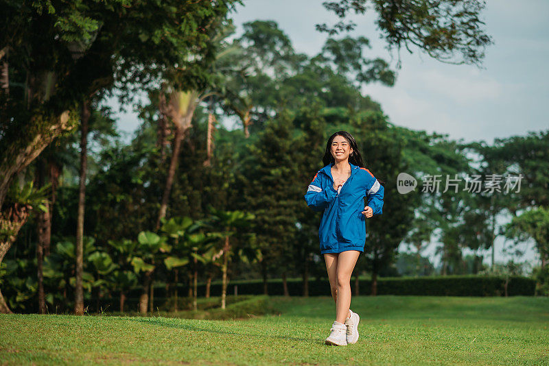 亚洲华裔少女穿着蓝色帽衫在公园慢跑
