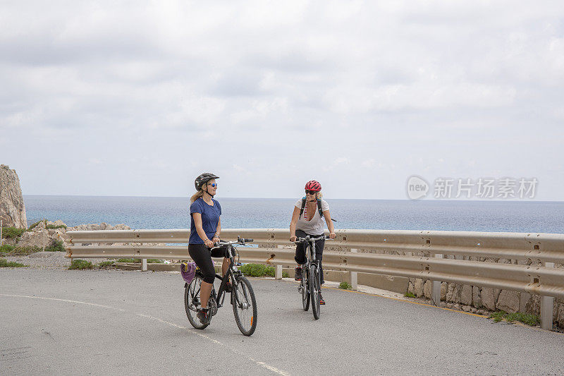 妈妈和女儿在空旷的沿海公路上骑自行车