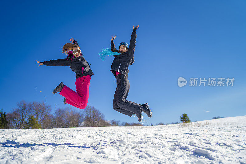 年轻的滑雪者在雪山上嬉戏跳跃