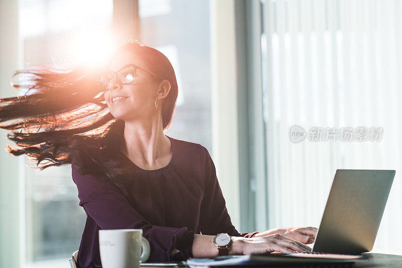 年轻的女商人在笔记本电脑上打字。