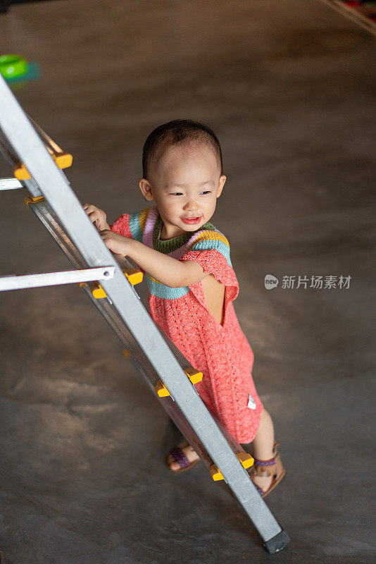 亚洲婴儿在学习走路时靠梯子支撑着自己