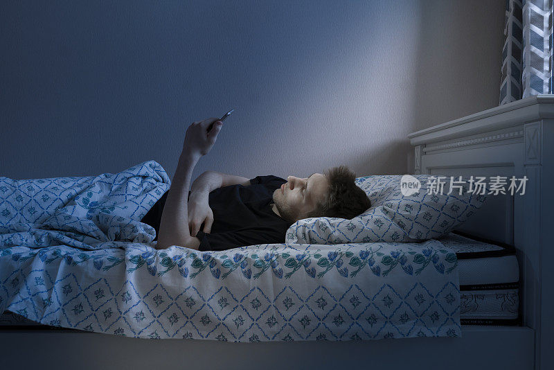 男人睡觉前躺着用手机，晚上躺在床上，沉迷于网络