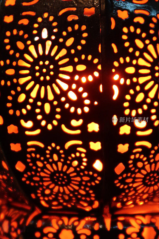 特写图像的照明金属灯笼，华丽的切口图案，发光的摩洛哥风格灯笼室内照明