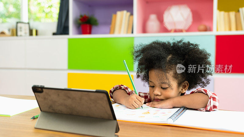 非洲裔美国小女孩使用数字平板电脑学习，学龄前儿童在家上学学习。儿童教育、自我隔离、冠状病毒爆发、社交距离或家庭教育概念