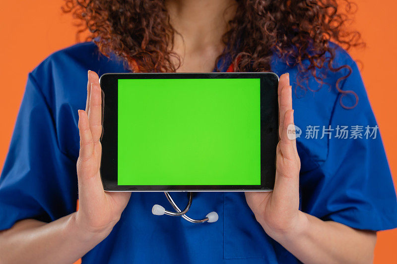 美丽的女医生显示数字平板与色度键绿色屏幕，积极的情绪