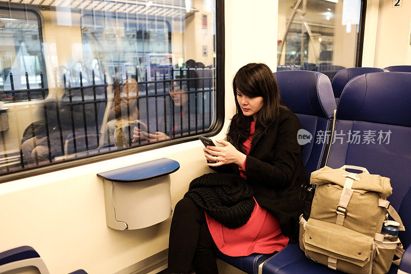 亚洲女性用智能手机乘火车旅行的肖像