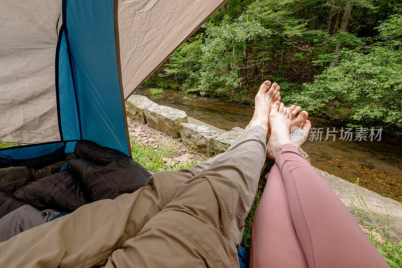 夏天的一天，在阿肯色州温泉国家公园，野营情侣们在帐篷外伸展双腿