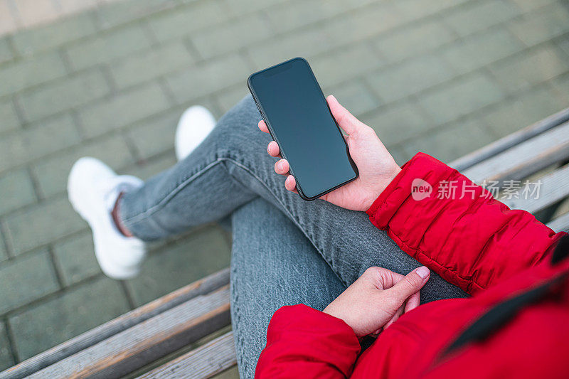 女人坐在长凳上使用智能手机