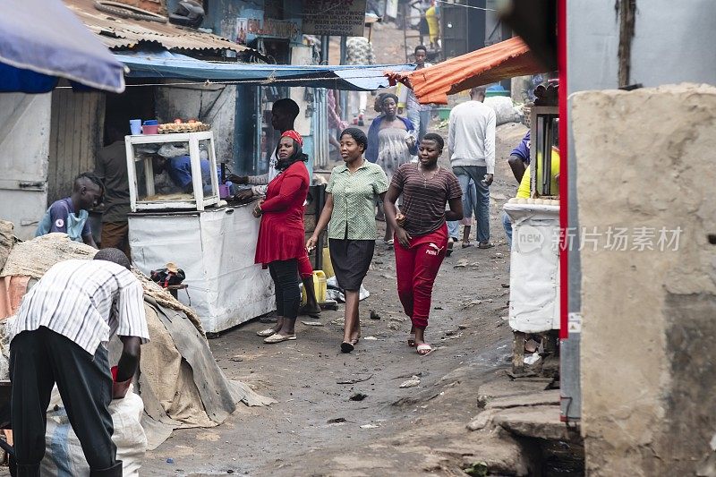 乌干达坎帕拉，妇女走过加丹加贫民窟的快餐店。