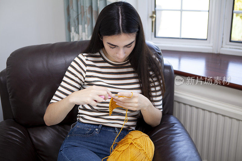 年轻女子用黄色毛线钩针编织