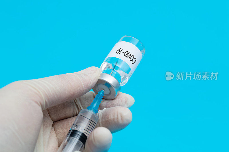 医生手持注射器和Covid-19疫苗瓶