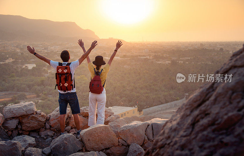 一对夫妇在阿联酋沙漠的山顶上欣赏日落的景色