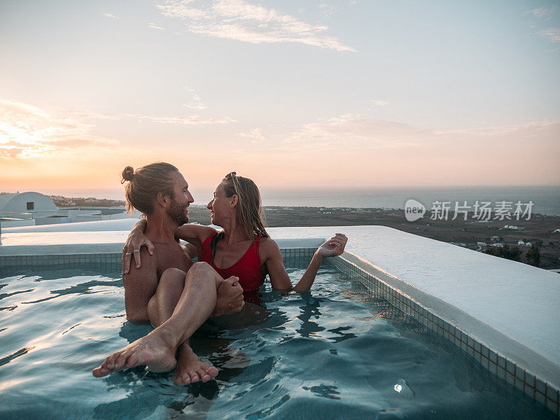 浪漫的情侣在热水浴缸里享受日落，男人抱着女朋友