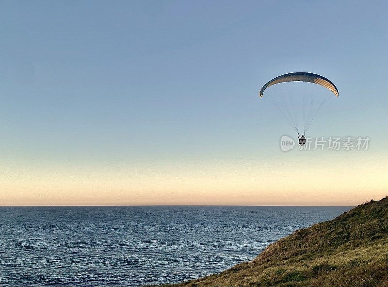 日落时从海岬滑翔伞