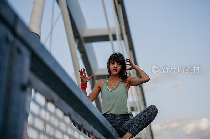 女运动员坐在桥的栅栏上