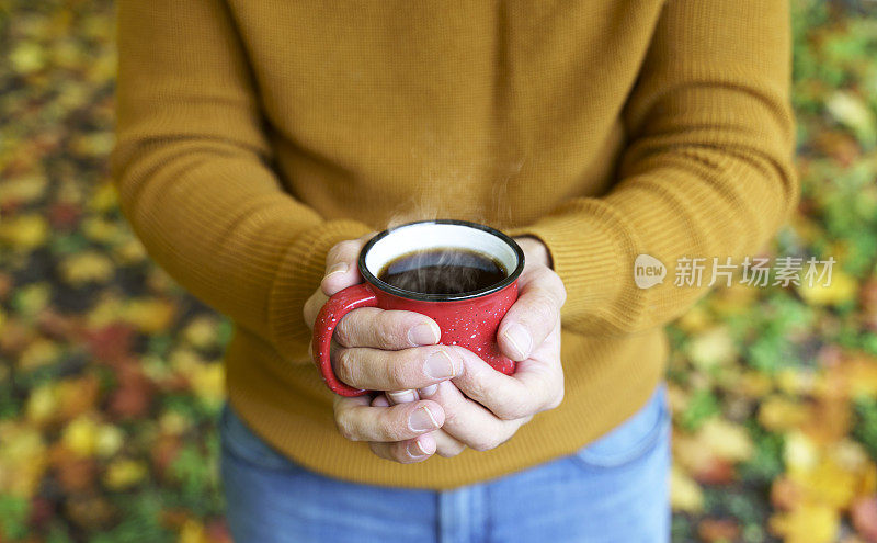 秋天喝着茶或咖啡，在十月黄叶的背景上。秋天的舒适和意境背景概念。